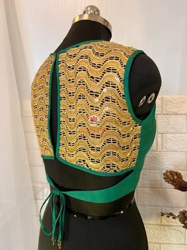 Angled back image of teal green silk blouse showing golden wave embroidery and tie closure