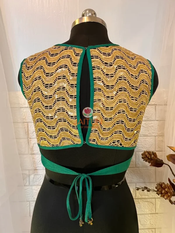 Back view of teal green silk blouse featuring open back and full golden embroidered design
