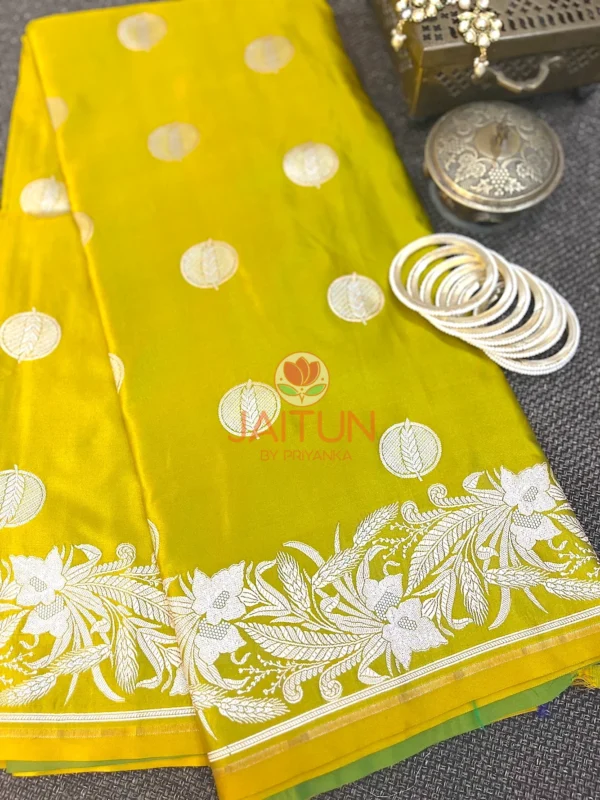 Lime Green Banarasi Silk Saree flatlay with silver zari floral border, circular motifs, and white bangles for traditional styling
