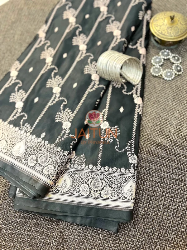 Noir Elegance Banarasi Silk Saree flatlay featuring intricate silver floral motifs, traditional zari border, and elegant accessories