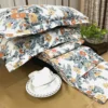 Autumn Garden Bloom bed sheet set styled with tableware, featuring vibrant orange and yellow floral pattern and leafy accents
