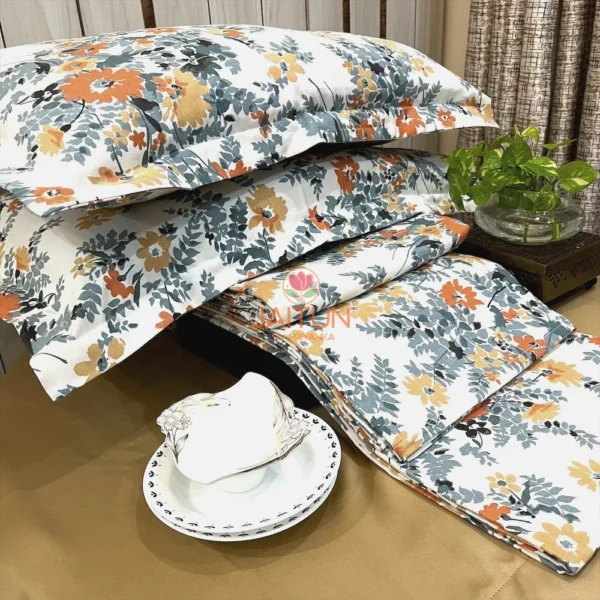 Autumn Garden Bloom bed sheet set styled with tableware, featuring vibrant orange and yellow floral pattern and leafy accents