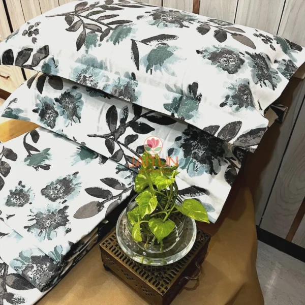 Arrangement of Azure Bloom Botanical Cotton Bedsheet Set on table, with floral print, pillow covers, and decorative accents.