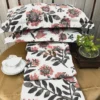 Stacked view of Bold Blossom Bed Sheet Set displaying vibrant floral prints and matching pillow covers on a table