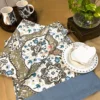 Heirloom Damask bed sheet set decor view with neatly arranged plates, cups, and glass vase on damask-printed fabric