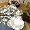 Heirloom Damask bed sheet set styled with matching plates and mugs, showing classic damask motifs in brown, blue, and ivory