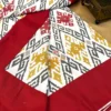 Ikat Harmony bed sheet showing rich maroon border and intricate mustard, grey, and red ikat pattern at the corner detail.