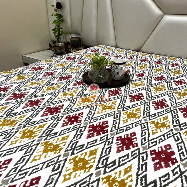 Ikat Harmony bed sheet spread on bed, highlighting all-over maroon and mustard ikat design in a bedroom setting.
