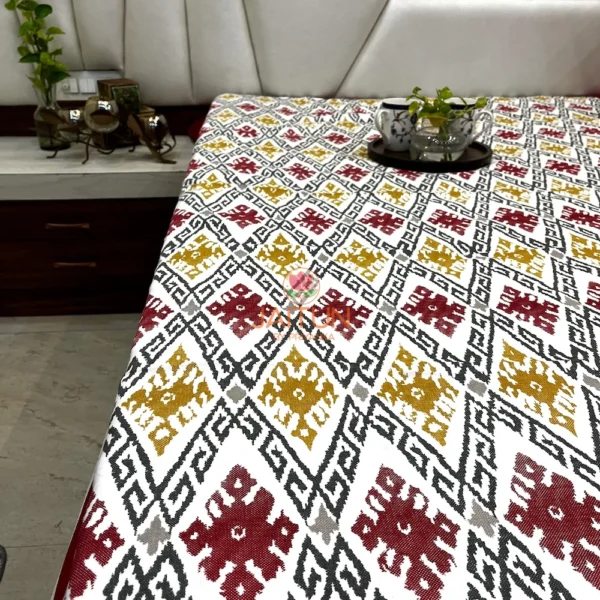 Room view of Ikat Harmony bed sheet showcasing bold maroon borders and vibrant ikat print across the full bed.