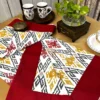 Ikat Harmony bed sheet set with maroon border, mustard and red ikat pattern, styled with tableware and decor for an elegant look.