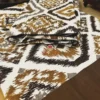 Closeup of Kalahari Ikat Geometric Bed sheet Set showing brown, mustard, and grey ikat pattern on crisp white fabric
