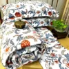 Royal Crimson Bloom cotton bed sheet set with floral-patterned pillows and quilt in deep crimson and blue, showcased with a decorative brass box.