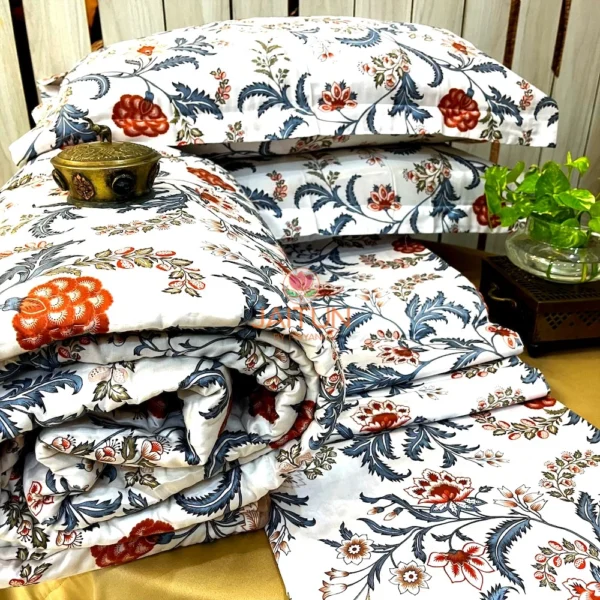 Royal Crimson Bloom cotton bed sheet set arranged with matching floral pillows and quilt, accented by a green plant on the nightstand.