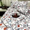 Royal Crimson Bloom cotton bed sheet set elegantly displayed on the bed with matching pillows and rolled quilt, styled with serving cups.