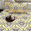Close view of Sunshine Elegance Yellow Bloom bed sheet showing pillows and detailed floral print in a bright yellow palette.