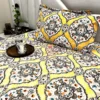 Sunshine Elegance Yellow Bloom bed sheet neatly spread on the bed with matching pillows and a wooden tray with mugs for a cozy setup.