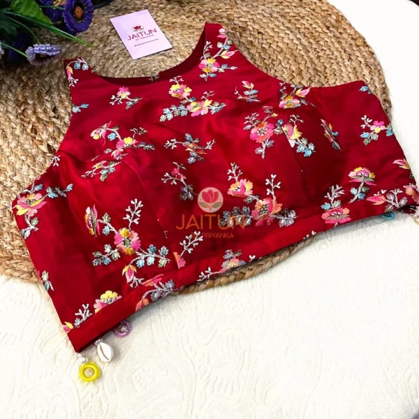 Detail of embellished hemline on Crimson Bloom Hand-Embroidered Wedding Blouse, adorned with vibrant floral motifs, beads, and pearl drops.