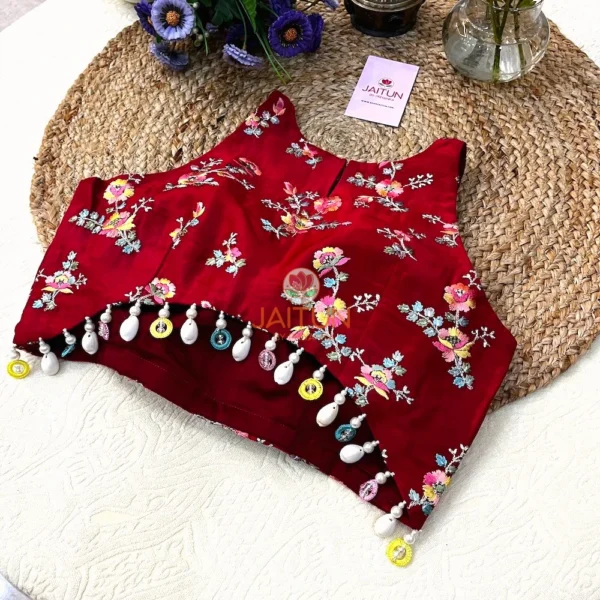 Detail shot of Crimson Bloom Hand-Embroidered Wedding Blouse featuring multicolor beadwork and pearl drop tassels on the hemline for a festive bridal look.