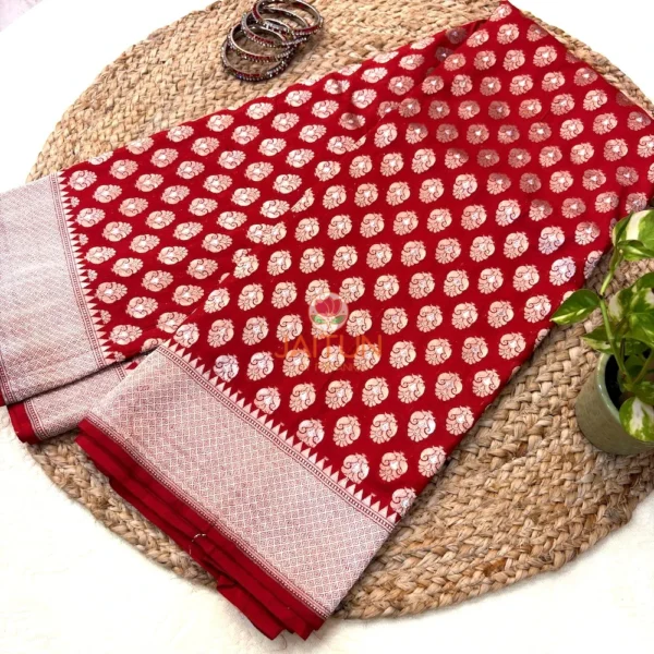 Full length Regal Red Pure Banarasi Silk Saree laid out on woven mat with golden bangles and green plant styled beside it 