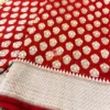 Regal Red Pure Banarasi Silk Saree top angle shot highlighting dense golden zari buta op angle view of Regal Red Pure Banarasi Silk Saree spread out, highlighting dense golden zari floral buta pattern