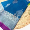 Folded teal blue pure Banarasi silk saree with silver zari border and contrast purple edge.