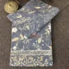 Folded Moonlit Meadow bed sheet showing slate blue floral pattern and decorative beige leafy border