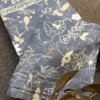 Close-up of Moonlit Meadow bed sheet featuring beige floral and botanical motifs on a slate blue base