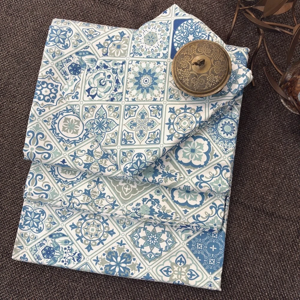 Moroccan Mist Bed Sheet folded and styled, showcasing blue and sage ornamental tile motifs